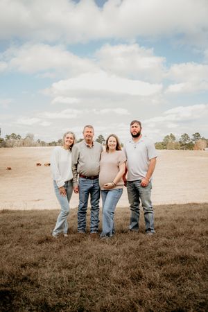 Small group standing together in casual attire against a rural field backdrop.