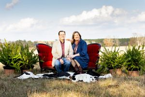 Family lounging on red vintage furniture in rustic outdoor setting.