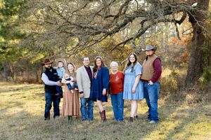 Large family group poses together outdoors in casual attire against a natural autumn backdrop.
