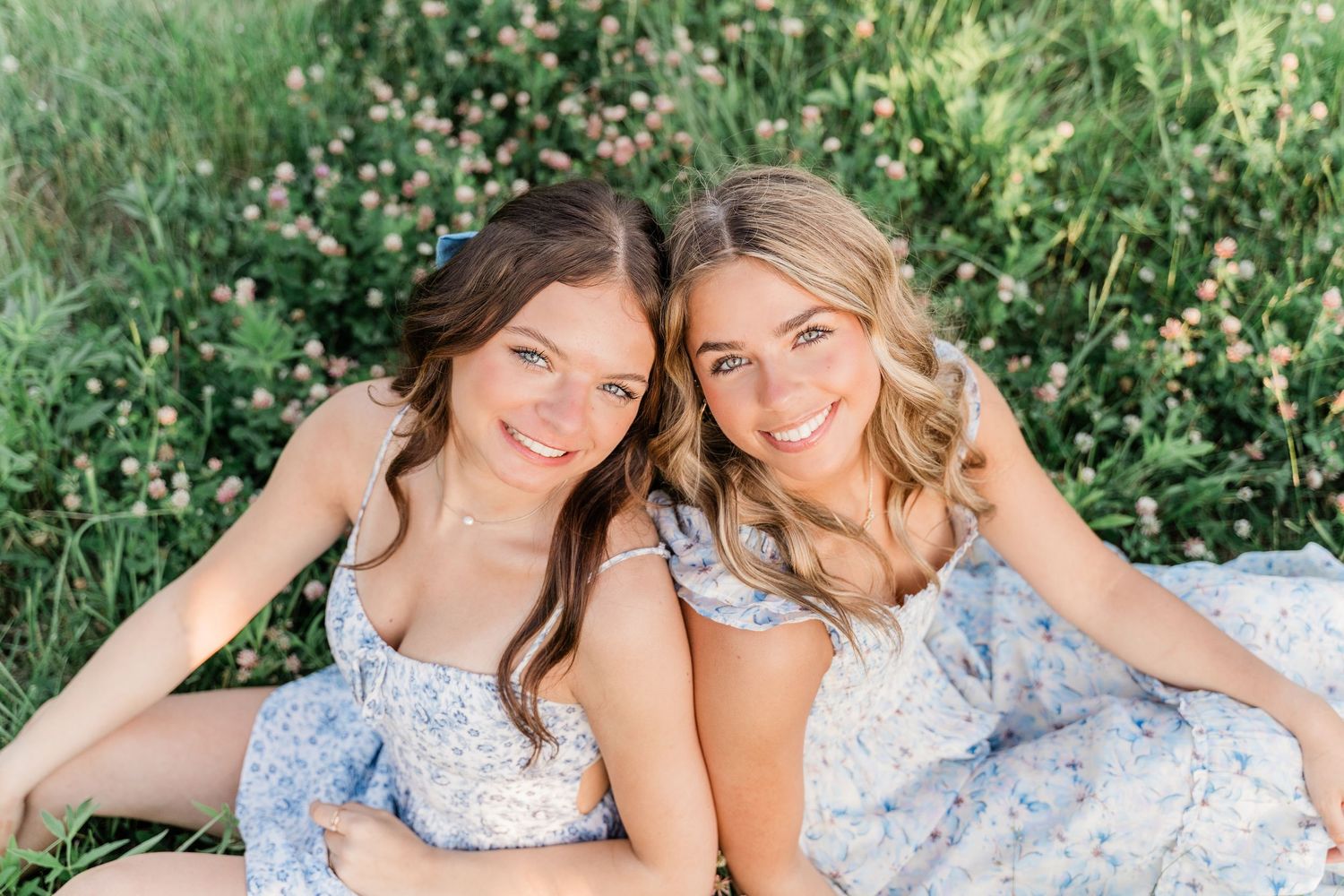 Toledo high school seniors in floral dresses pose together on grass during an outdoor photo session.
