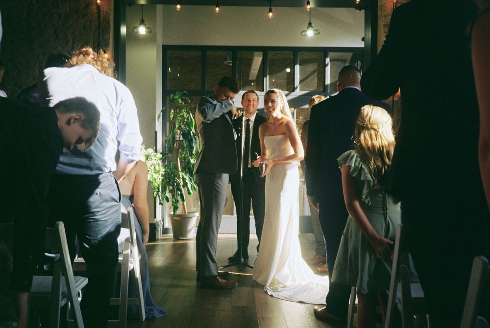 A wedding ceremony processional in an intimate indoor venue with ambient lighting.