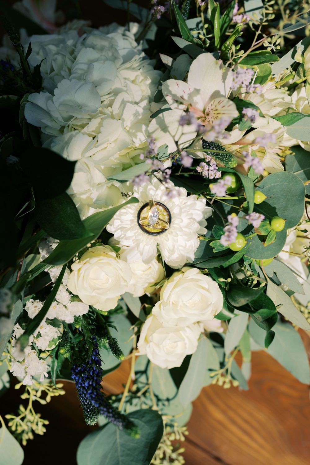 A close-up sequence of wedding rings nestled among delicate white flowers and green foliage in a bridal bouquet.