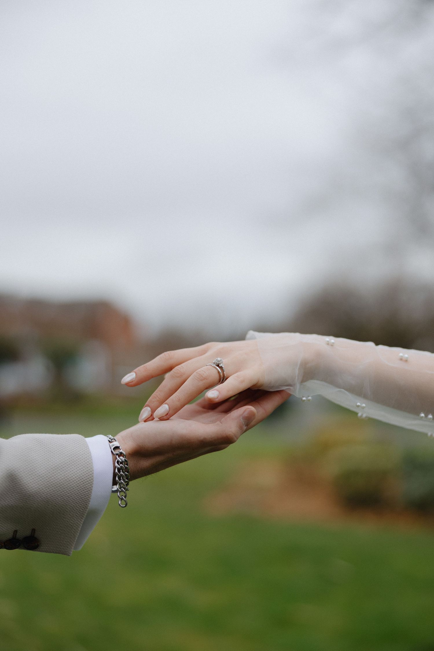 A close-up sequence of hands reaching out to each other against a blurred green outdoor background.
