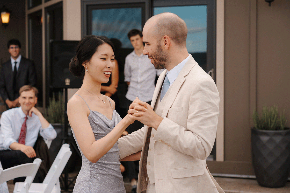 Couple dancing together at an elegant wedding reception while guests watch from tables in the background.