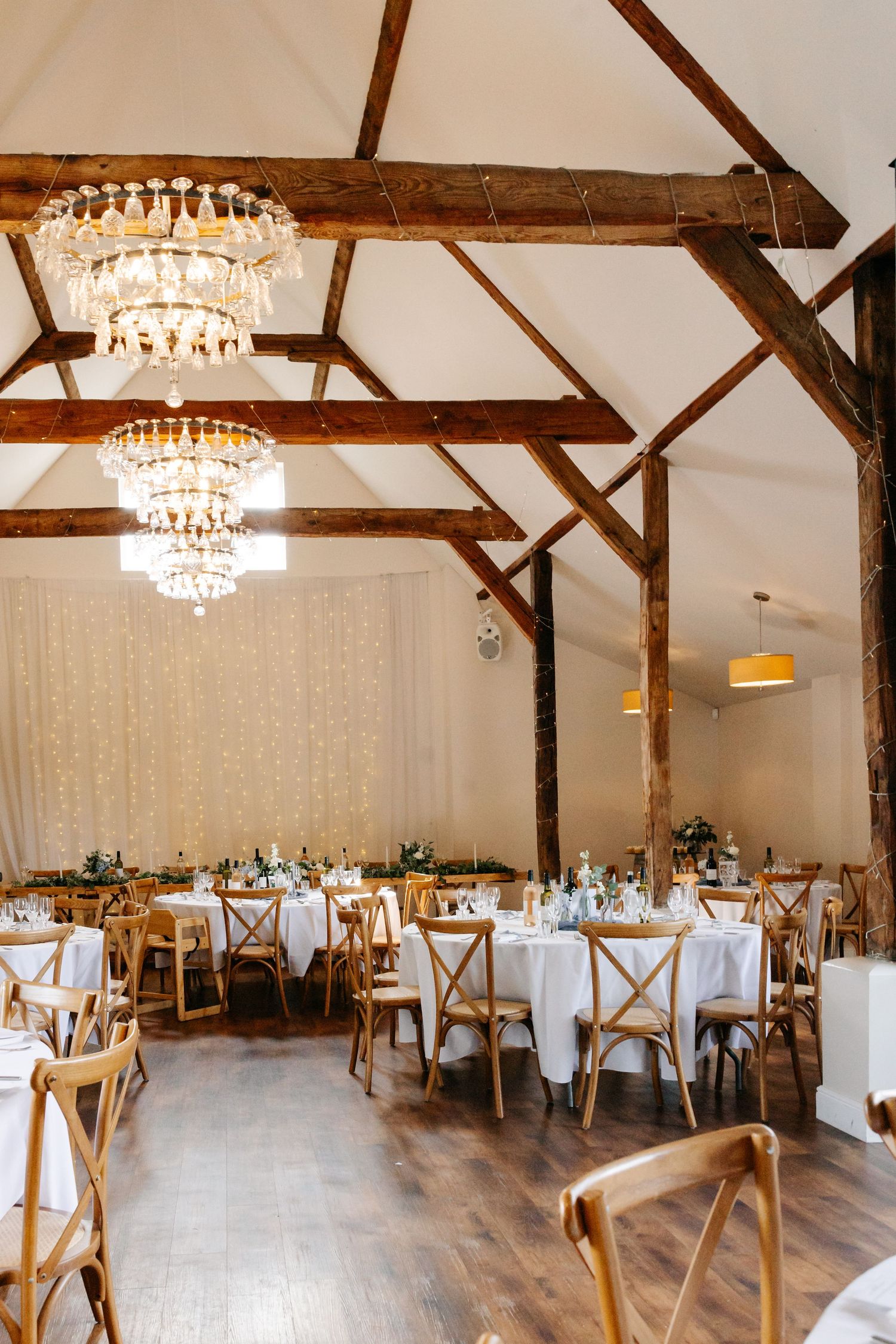 Wickham Estate wedding venue with elegant crystal chandeliers, wooden beams, and tables set for a reception.