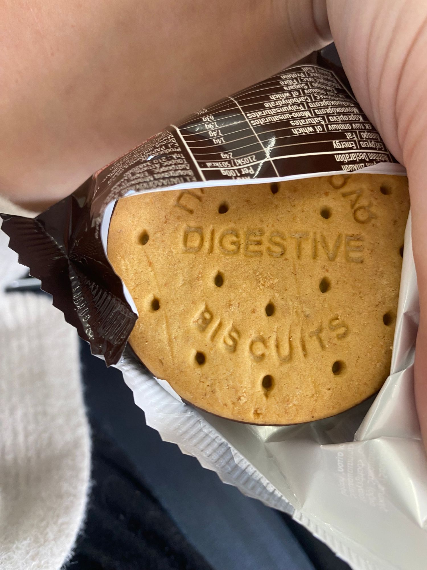 A digestive biscuit being dipped in dark chocolate shows different stages of coating from multiple angles.