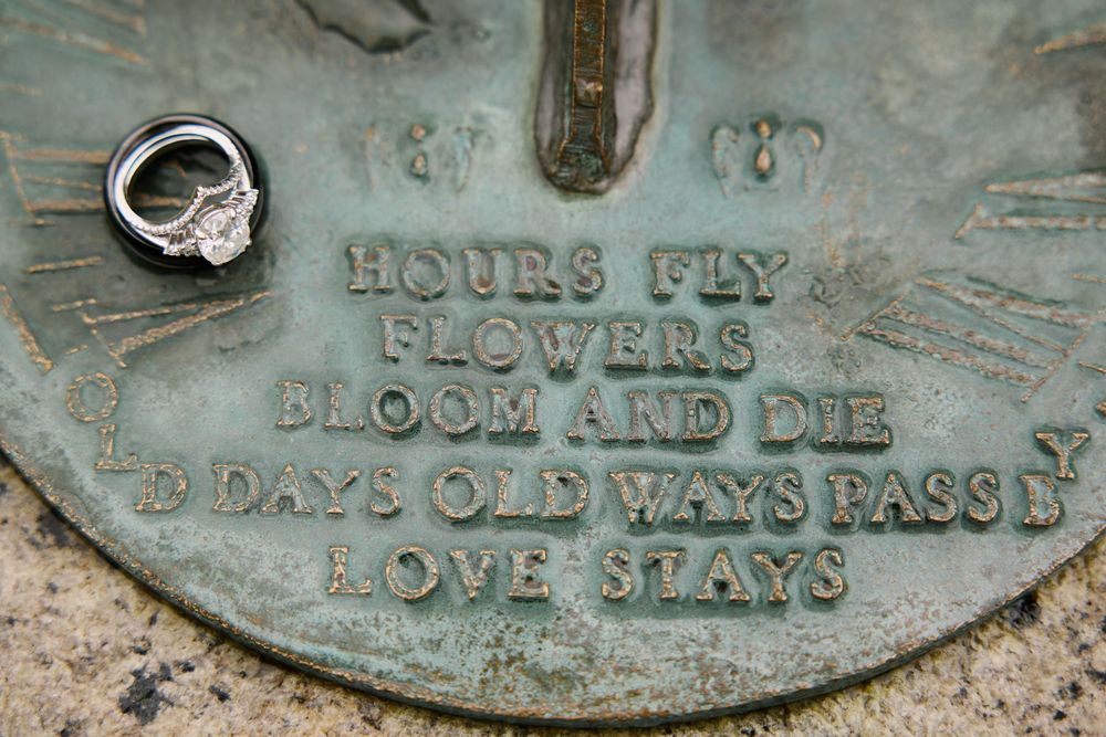 Diamond engagement ring on vintage sundial engraved with Love Stays quote.