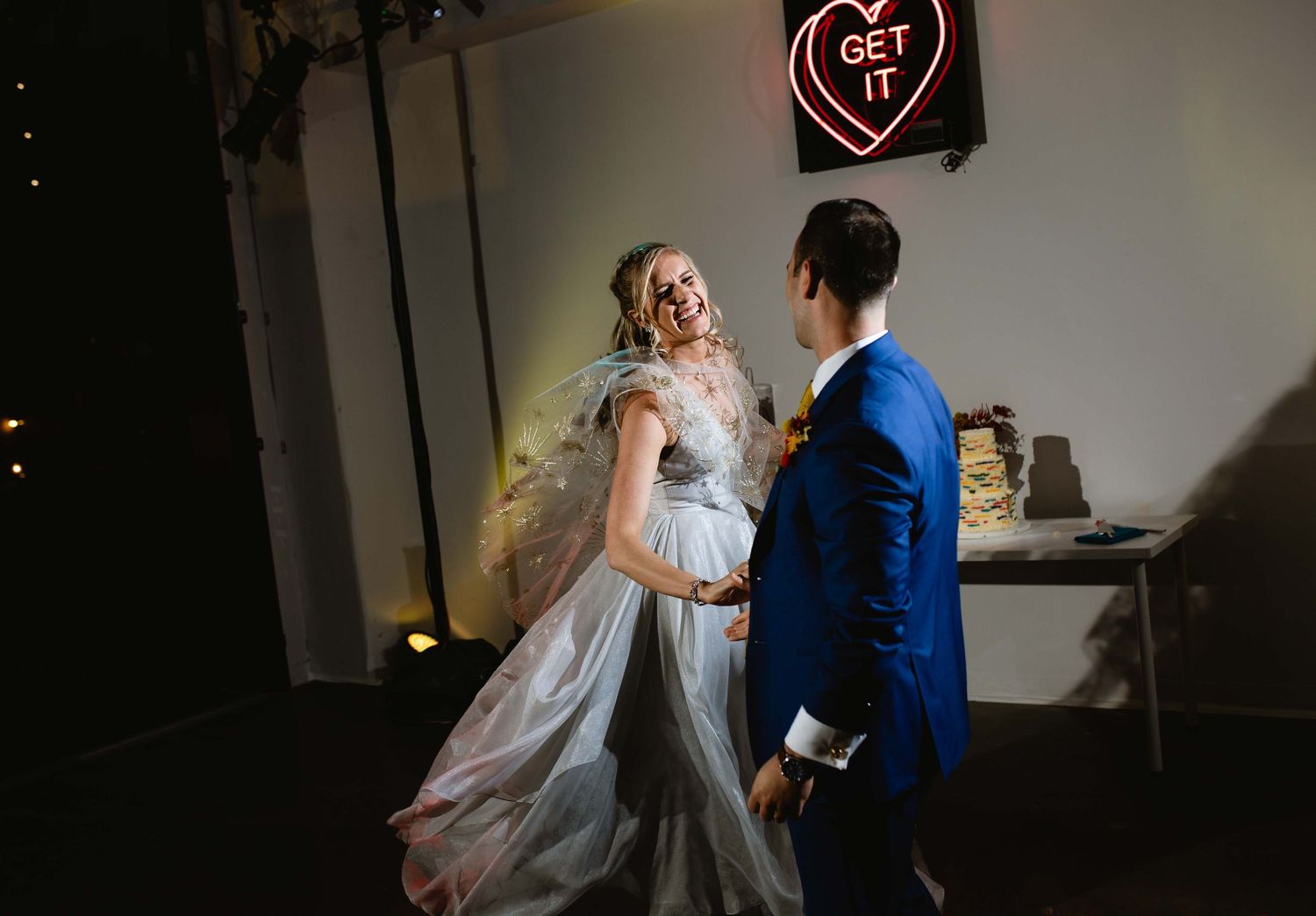 A couple in wedding attire dances together in a dimly lit room creating a romantic atmosphere.