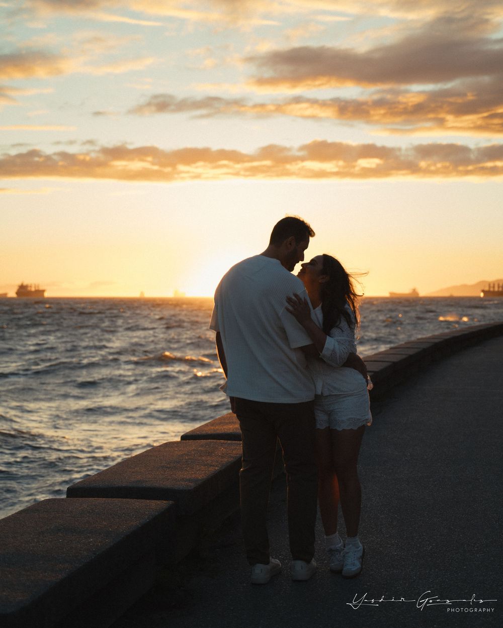 Romantic silhouette of a couple embracing on a waterfront promenade at a stunning golden sunset.

Vancouver Canada Scene