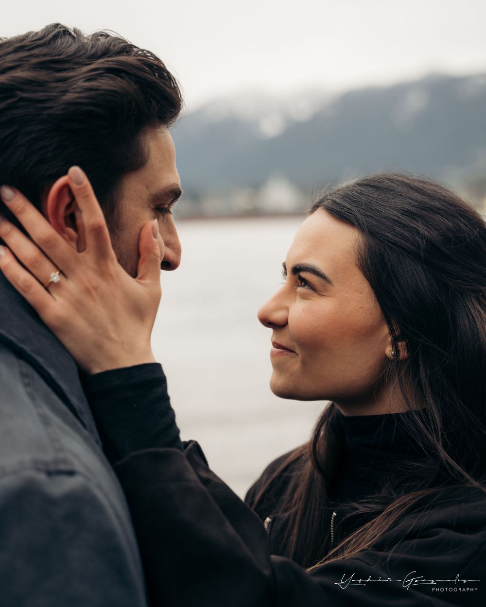 Couple sharing an intimate moment, woman touching mans face showing engagement ring with mountains behind.

Vancouver Canada Scene