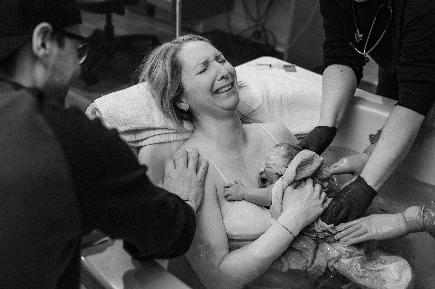 Black and white photo series showing tender moments between a couple during labor and delivery at hospital.