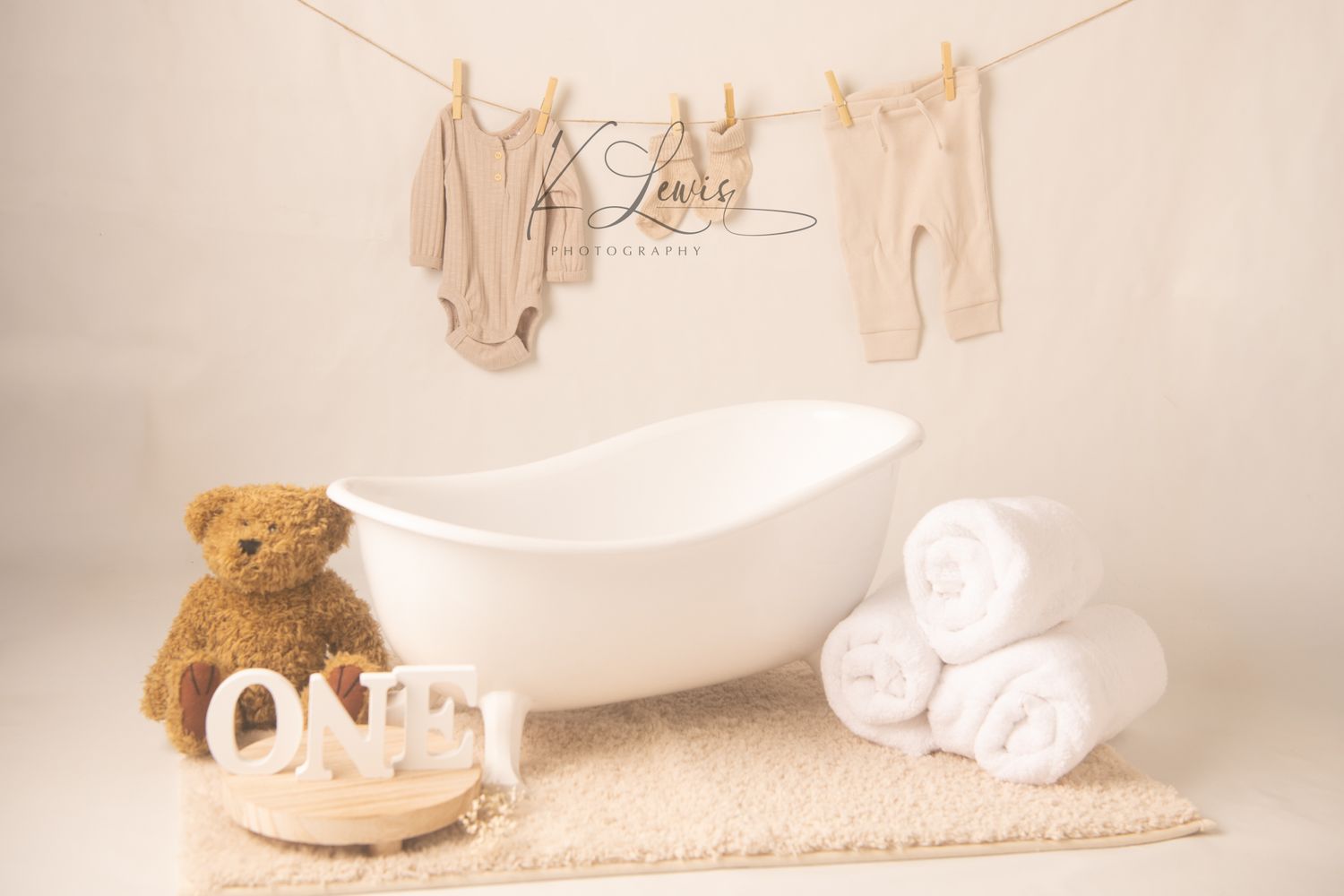 White teepee tent with ONE banner and teddy bear on fluffy rug for first birthday photo shoot.