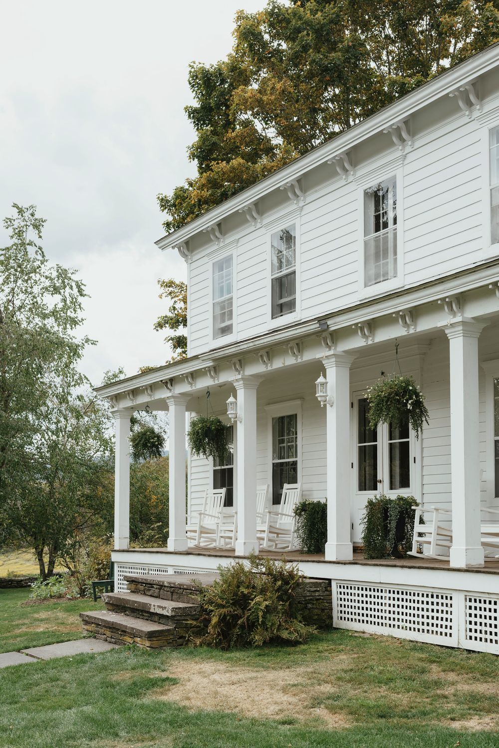 A white farmhouse with a wraparound porch and lattice details shown from multiple angles in a collage format.