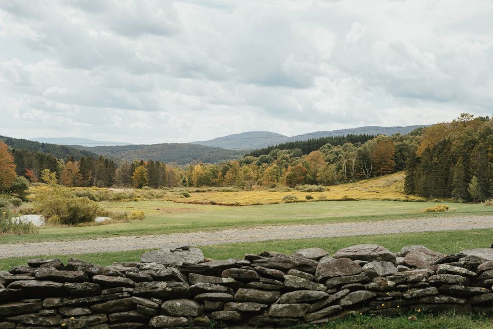 Rolling hills and stone walls stretch across a scenic autumn landscape in the countryside.