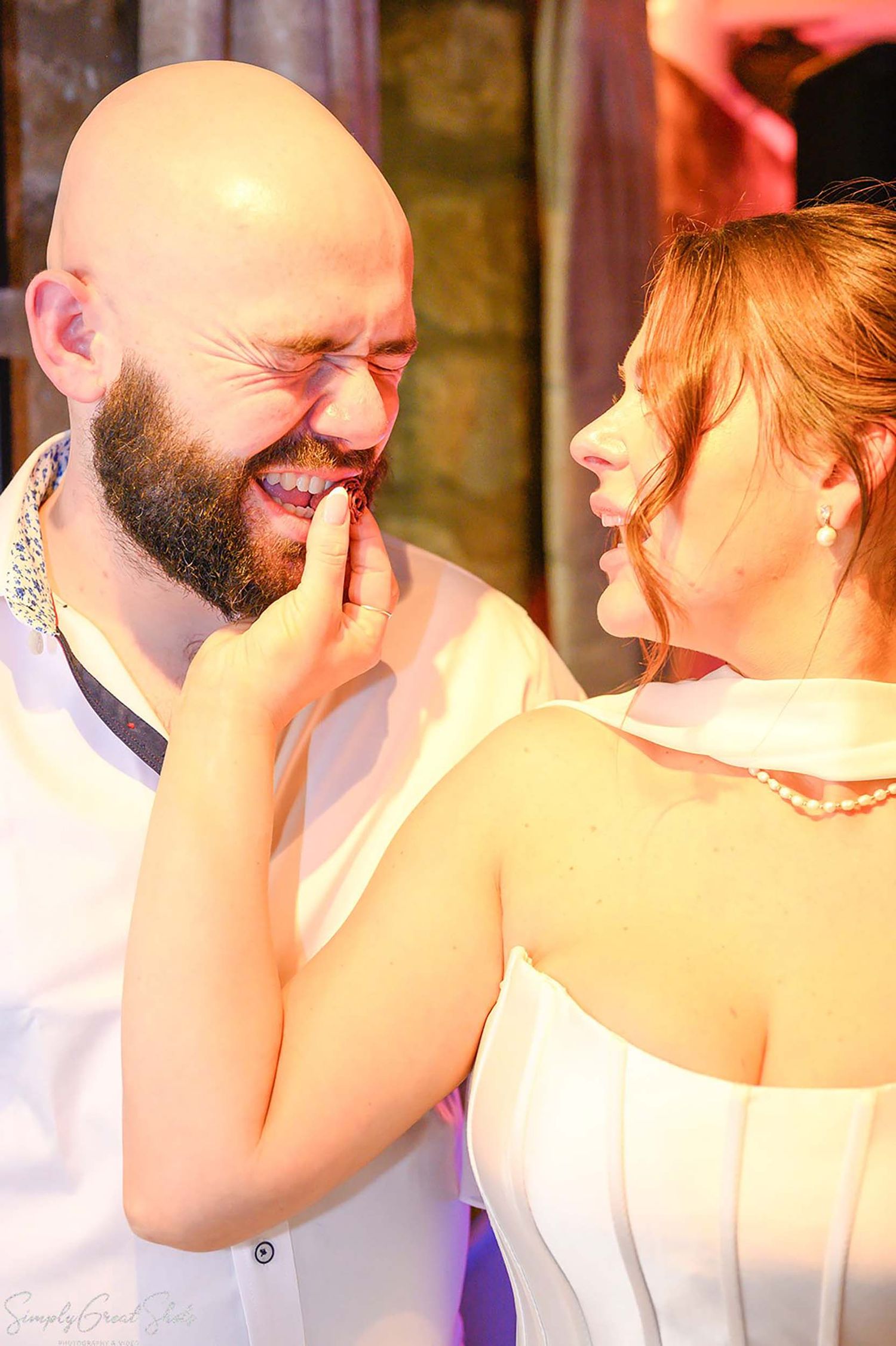 Bride Stacey feeding wedding cake to groom Jack at The Saxon Mill, Warwick — candid wedding reception photography by SimplyGreatShots