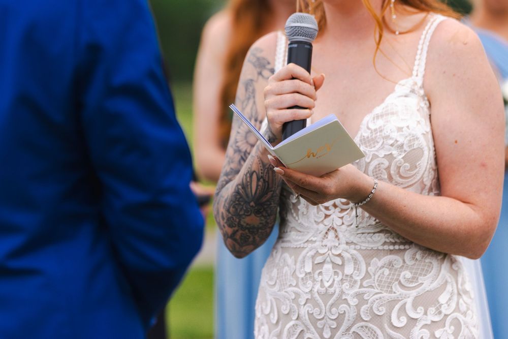 Wedding ceremony participants in formal attire gather outdoors against a blue sky backdrop.