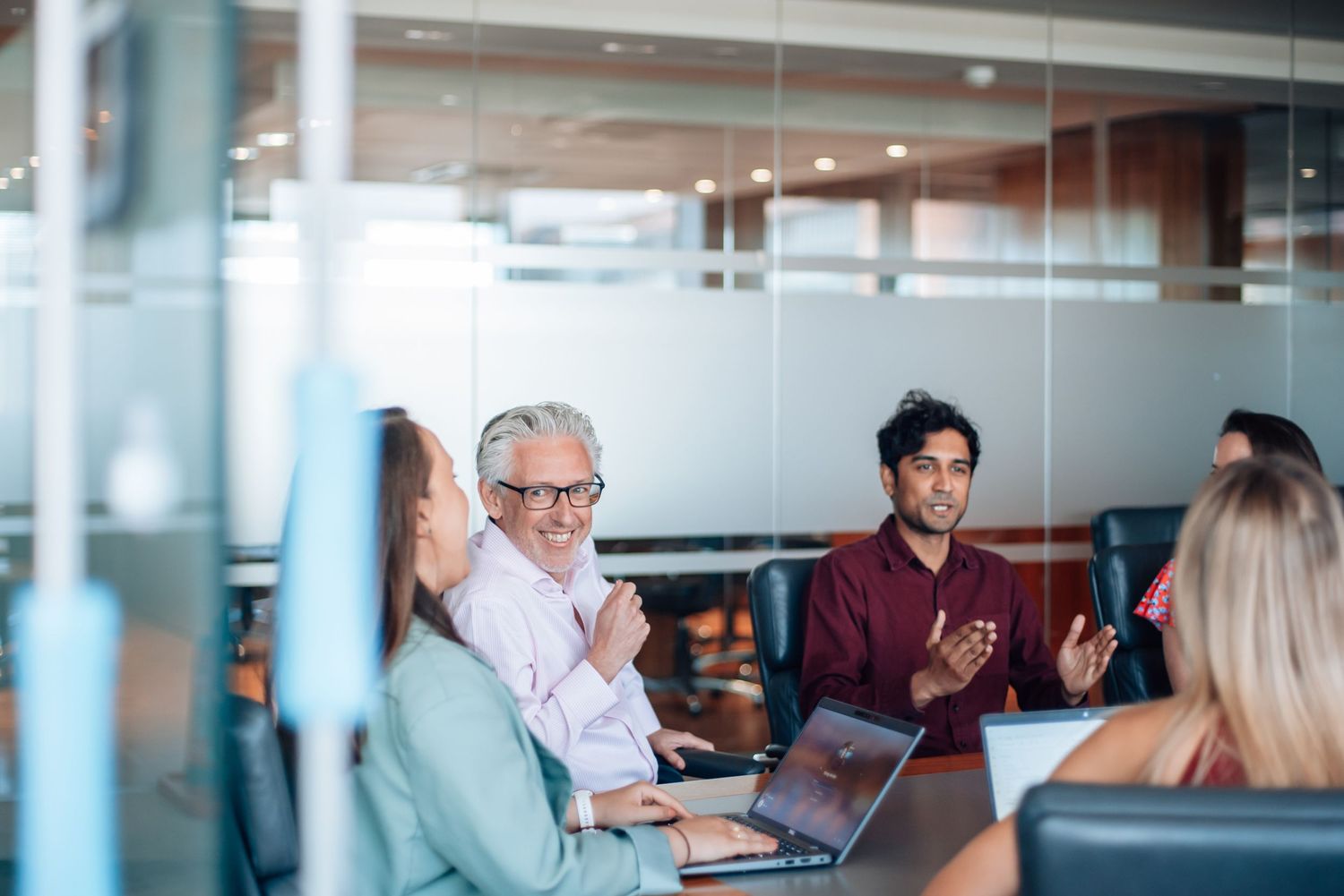 Business professionals engaged in a productive meeting around a conference table with laptops in a modern office.