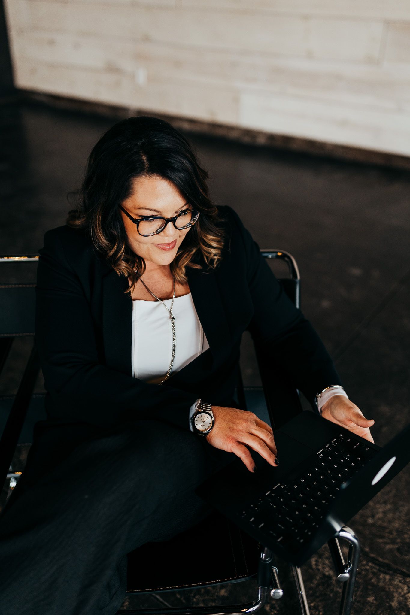 A person wearing glasses types on a laptop keyboard in a dimly lit setting with multiple angles shown.
