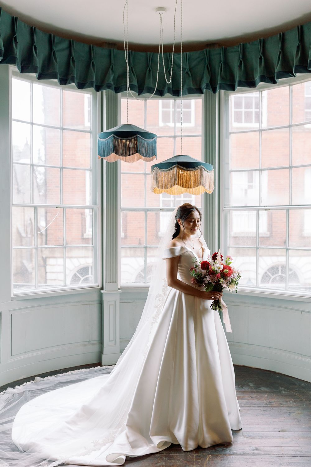 An elegant bridal portrait in a sunlit room with green valances and large windows.