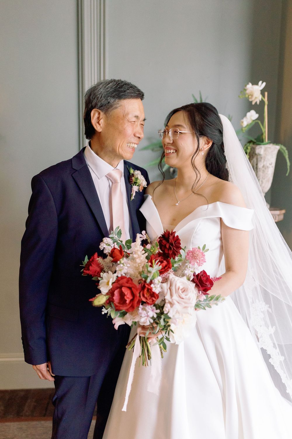 Romantic wedding portraits showing tender moments between couple with beautiful red and pink floral bouquet.
