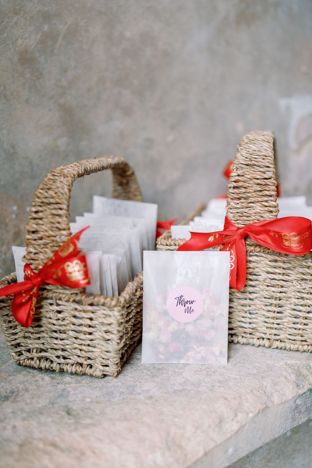 Sequence of woven baskets with white cards and red ribbons arranged in a line on a textured surface from a wedding day by Maddie Waters