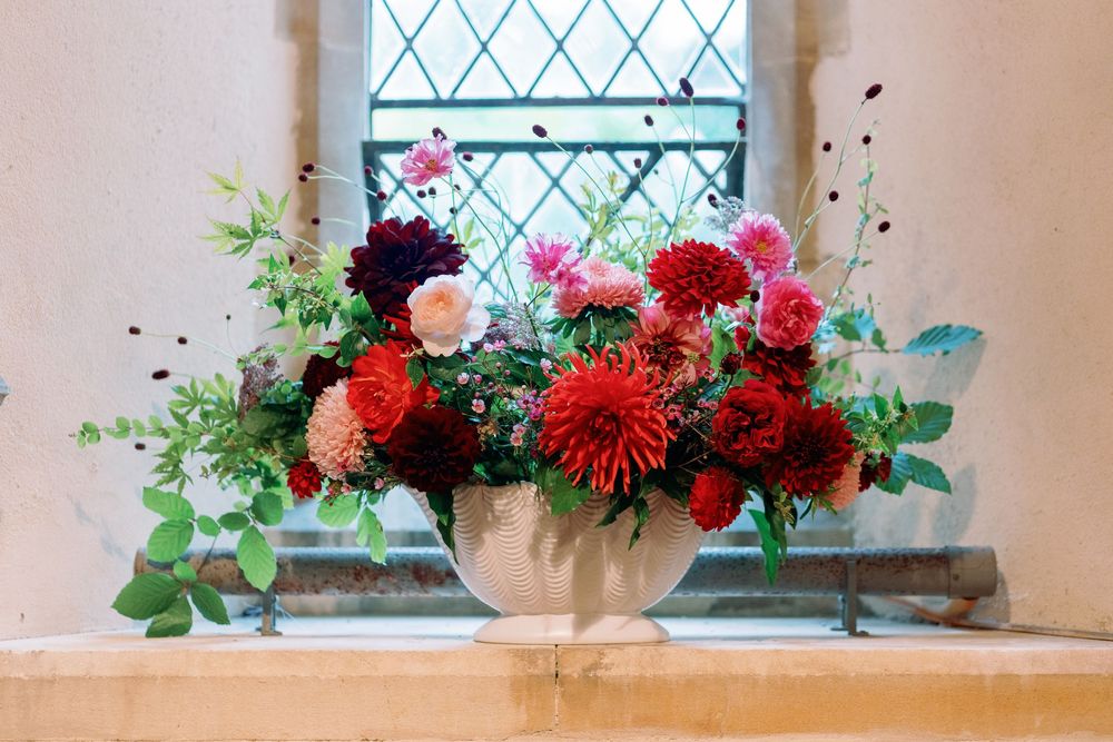 Colorful floral arrangements with pink and red blooms decorate church windows taken by Maddie Waters Photography