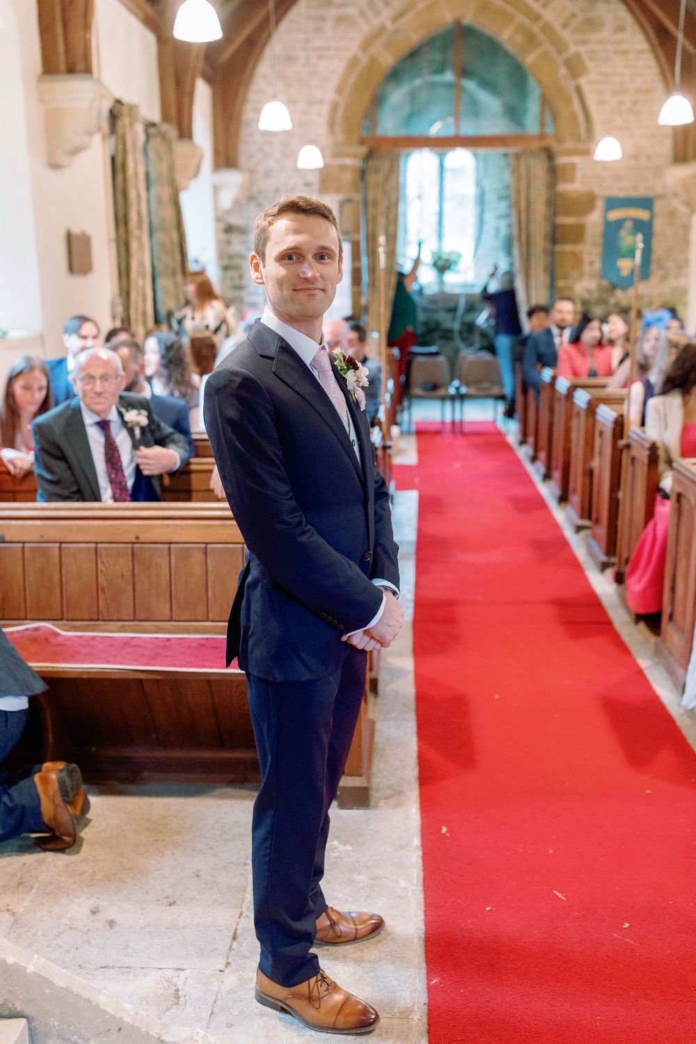 Groom waiting at the top of a church aisle for his Bride taken by Maddie Waters Photography
