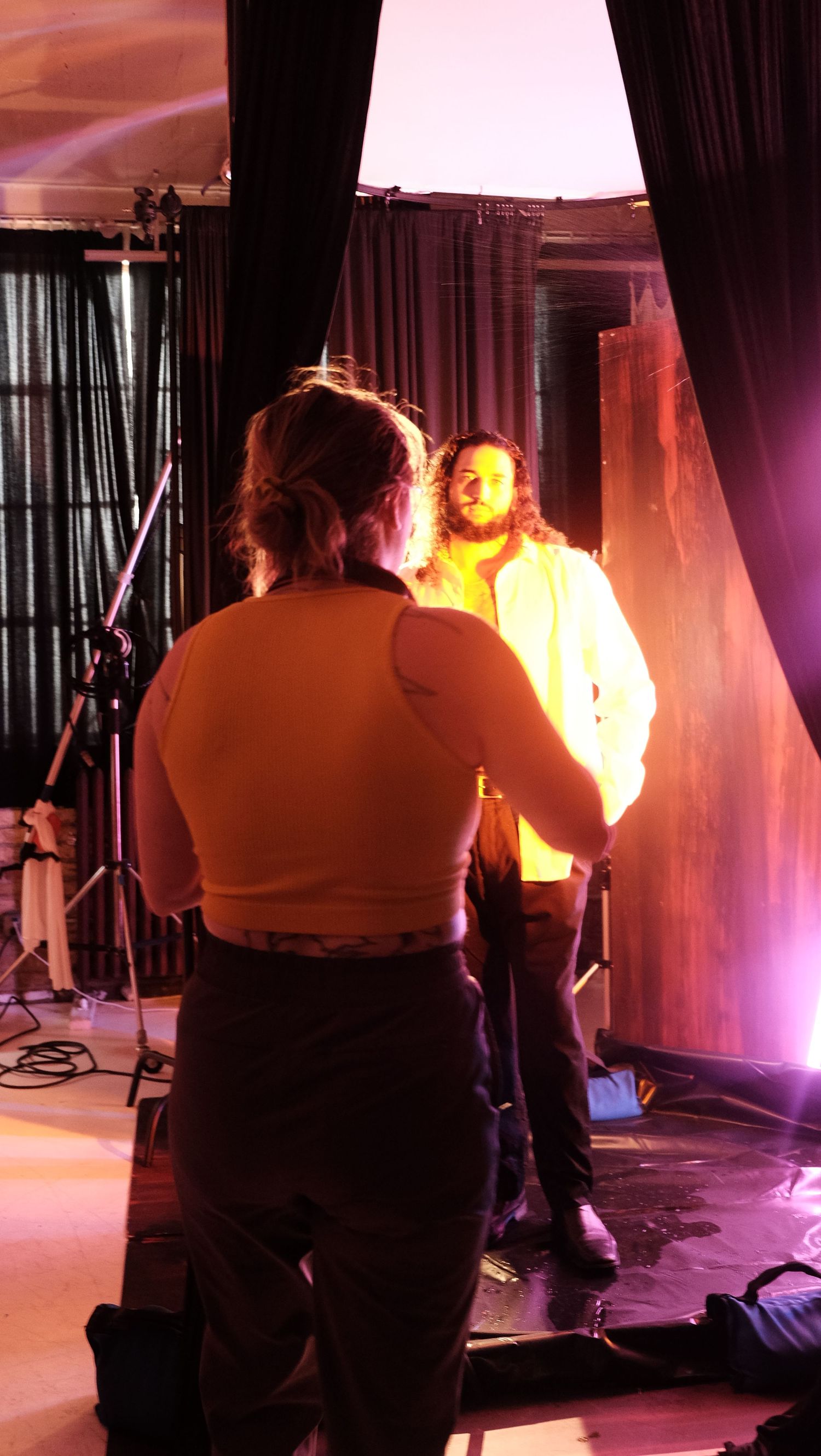 Photographer captures performer on stage with dramatic orange and purple lighting during a live concert setup.