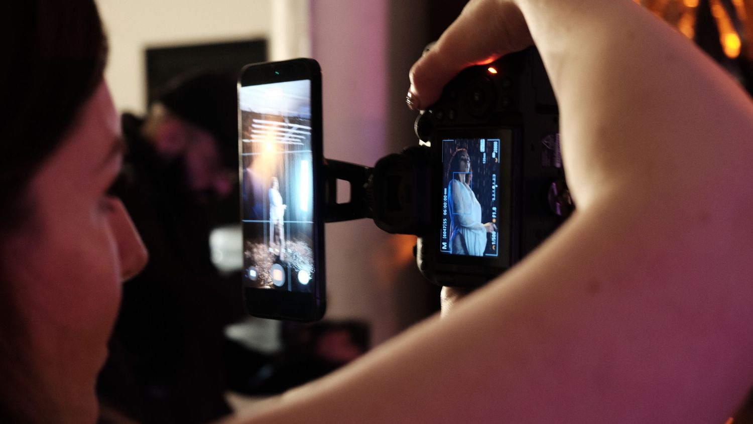 Someone takes a photo of a phone screen displaying a video call or selfie camera view in a dimly lit room.