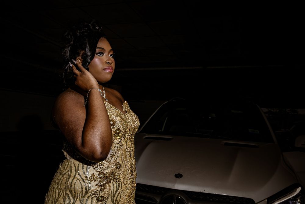 Woman in a sparkling gold dress poses against dark background while wearing headphones.