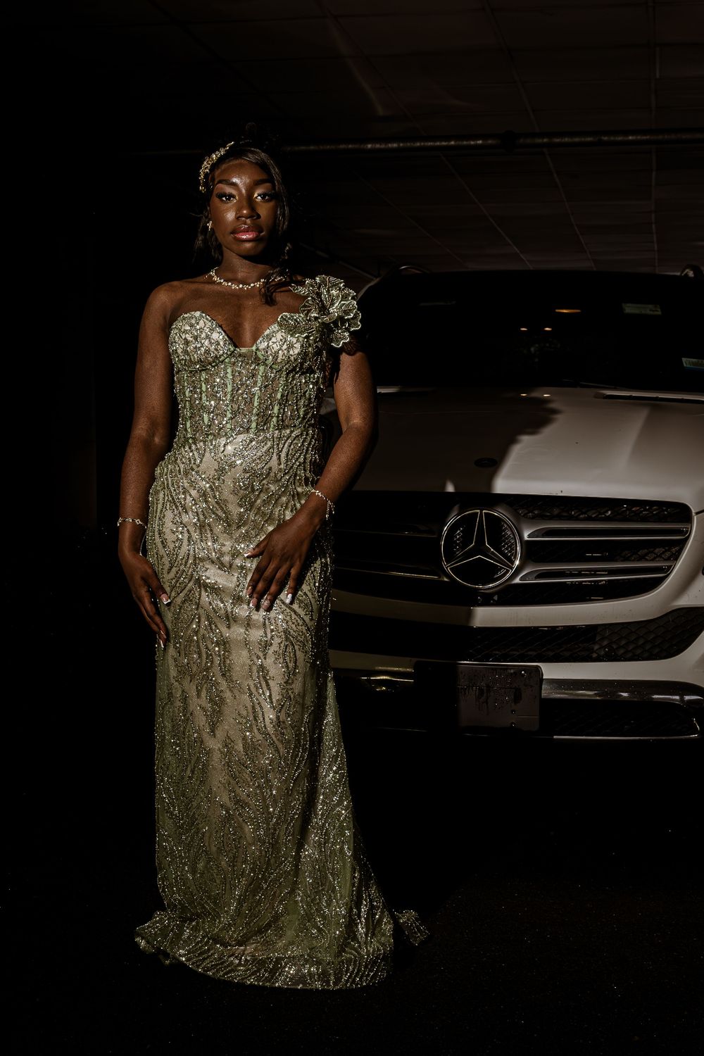 Elegant gold evening gown with intricate embroidery shown in front of a Mercedes-Benz vehicle at night.