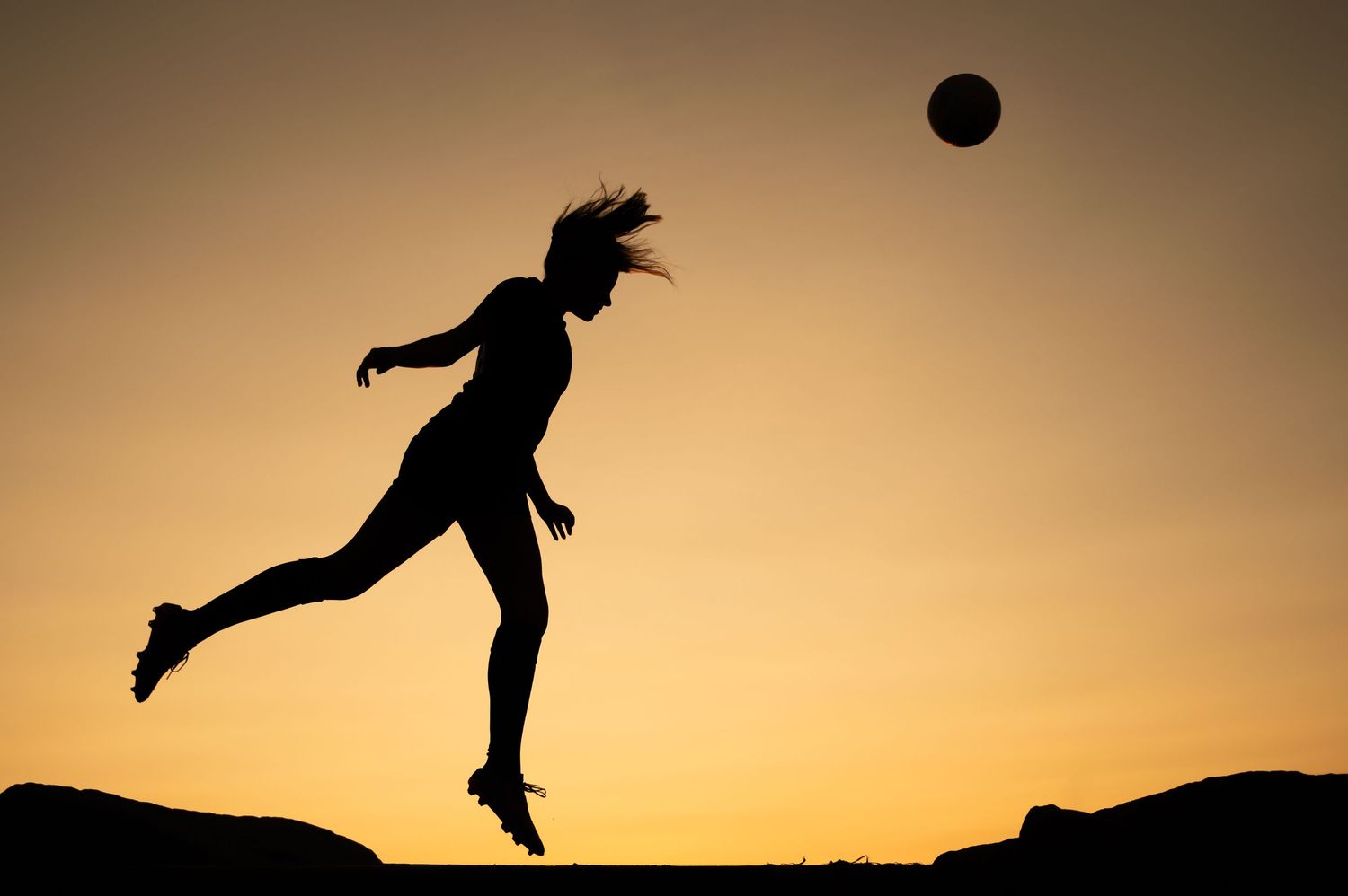 Silhouette of a person jumping on rocks against a golden sunset sky creating a dynamic action sequence.