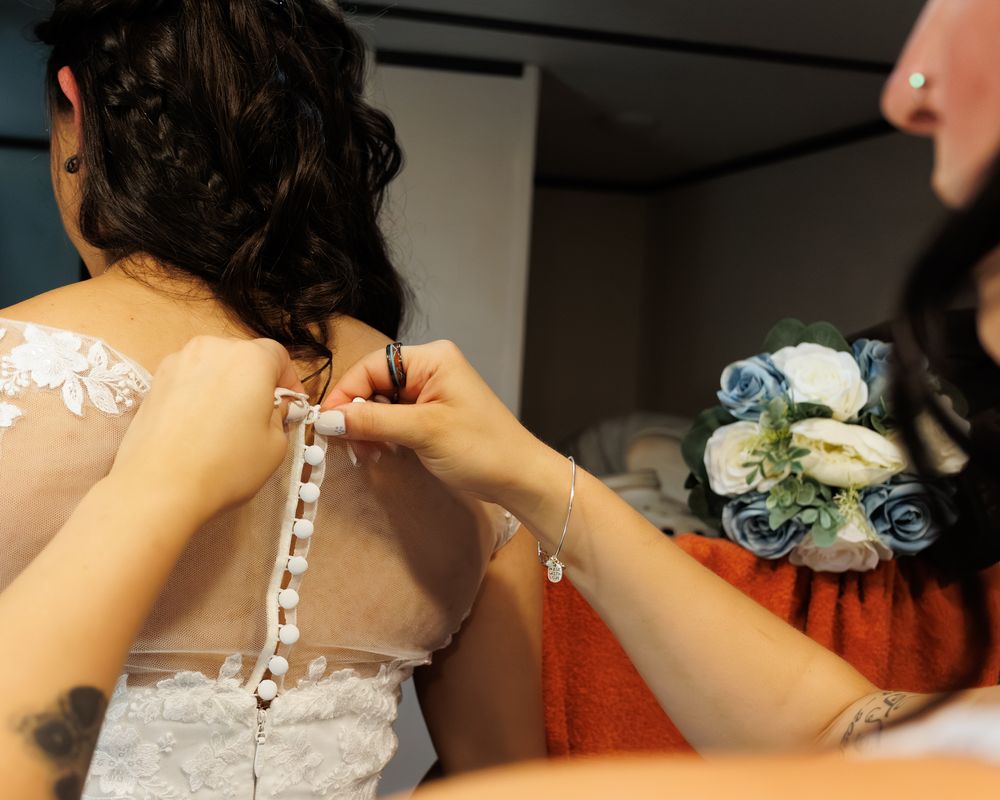 Close-up shot of bridesmaid fastening the delicate buttons on a Montana brides wedding dress.