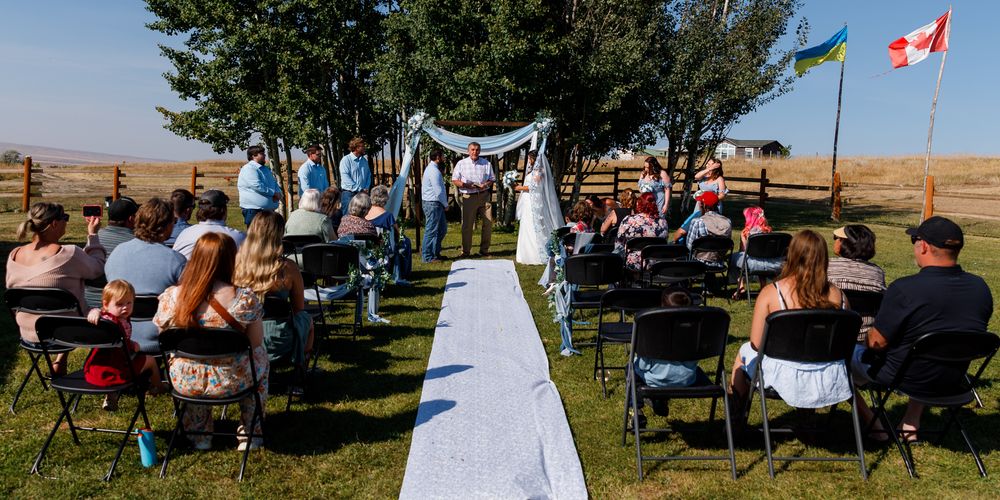 Outdoor Montana wedding ceremony with white chairs and a the rustic Montana outdoors for a backdrop.
