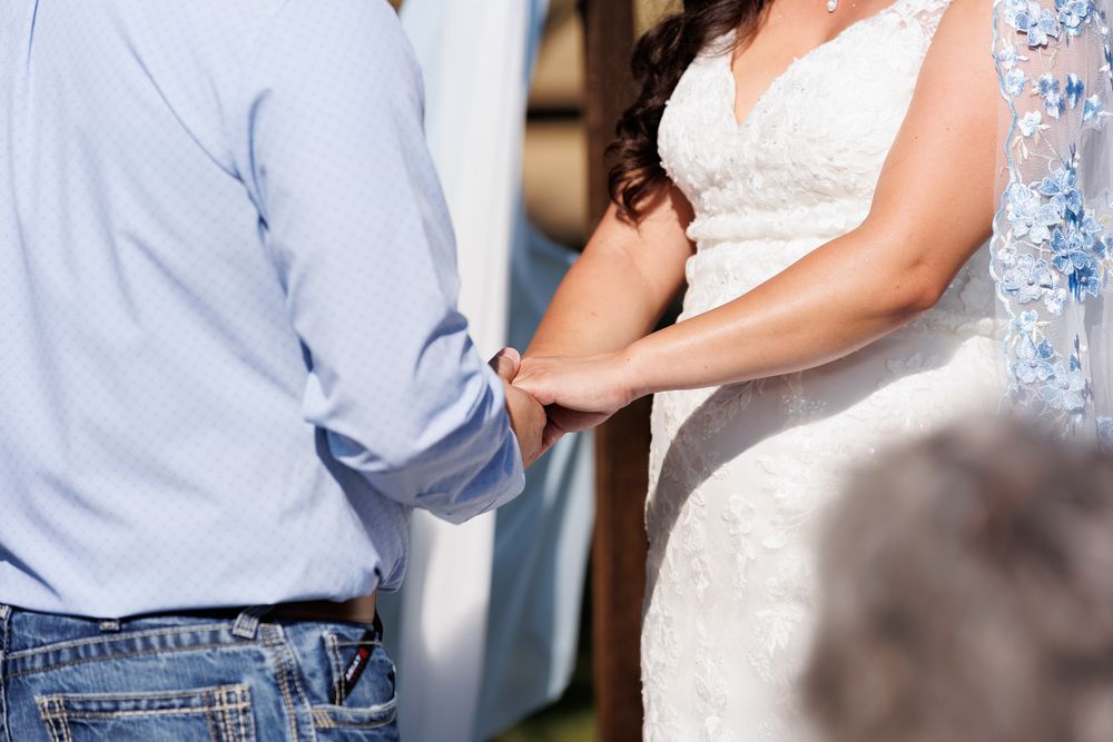 close up of bride and groom holding hands at alter.