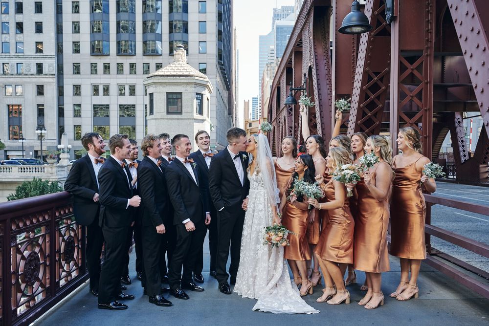 Wedding party poses on a Chicago bridge with bridesmaids in copper dresses and groomsmen in black suits.