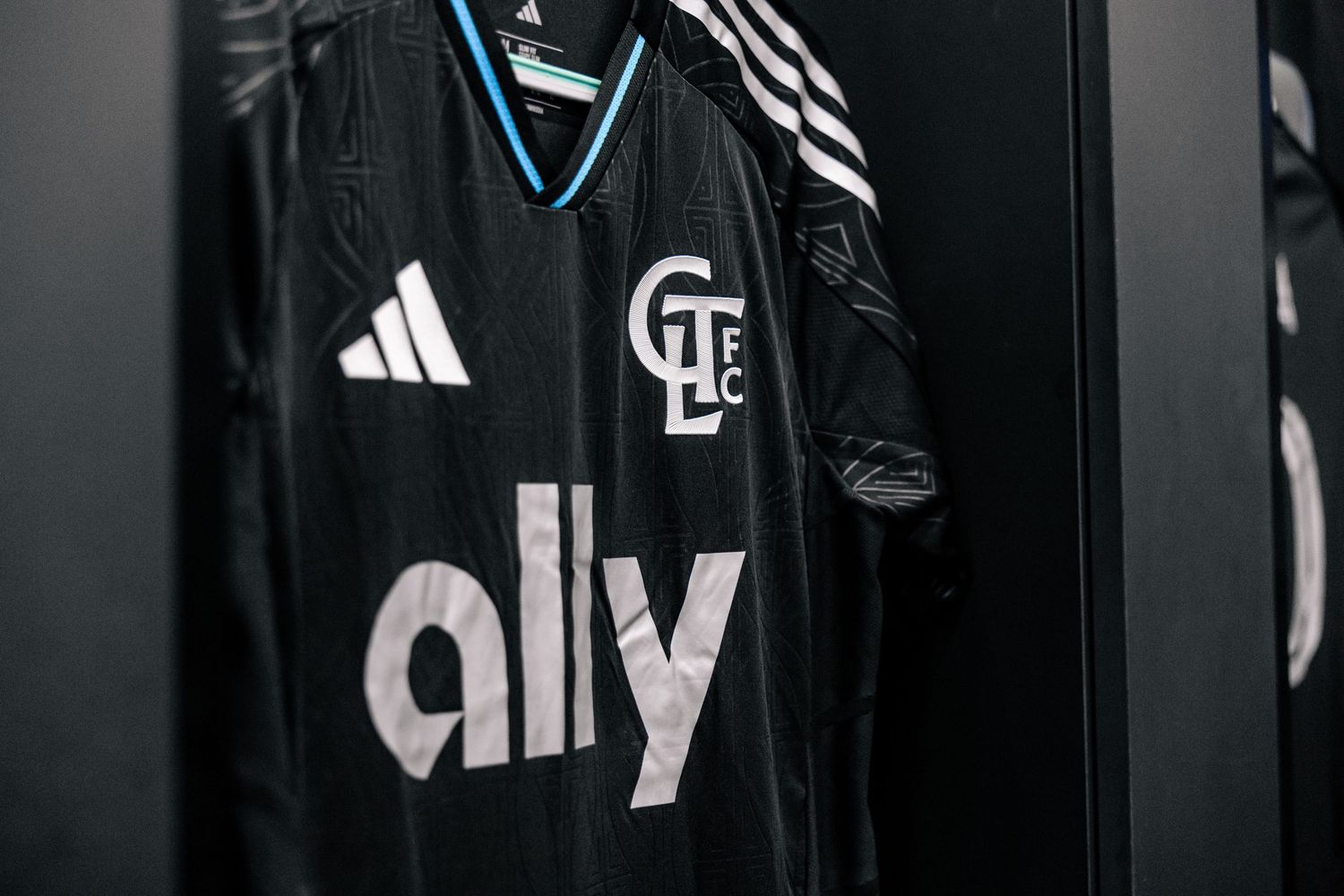Charlotte FC black Fortress Kit jersey with ally sponsor hanging in the locker room close-up.