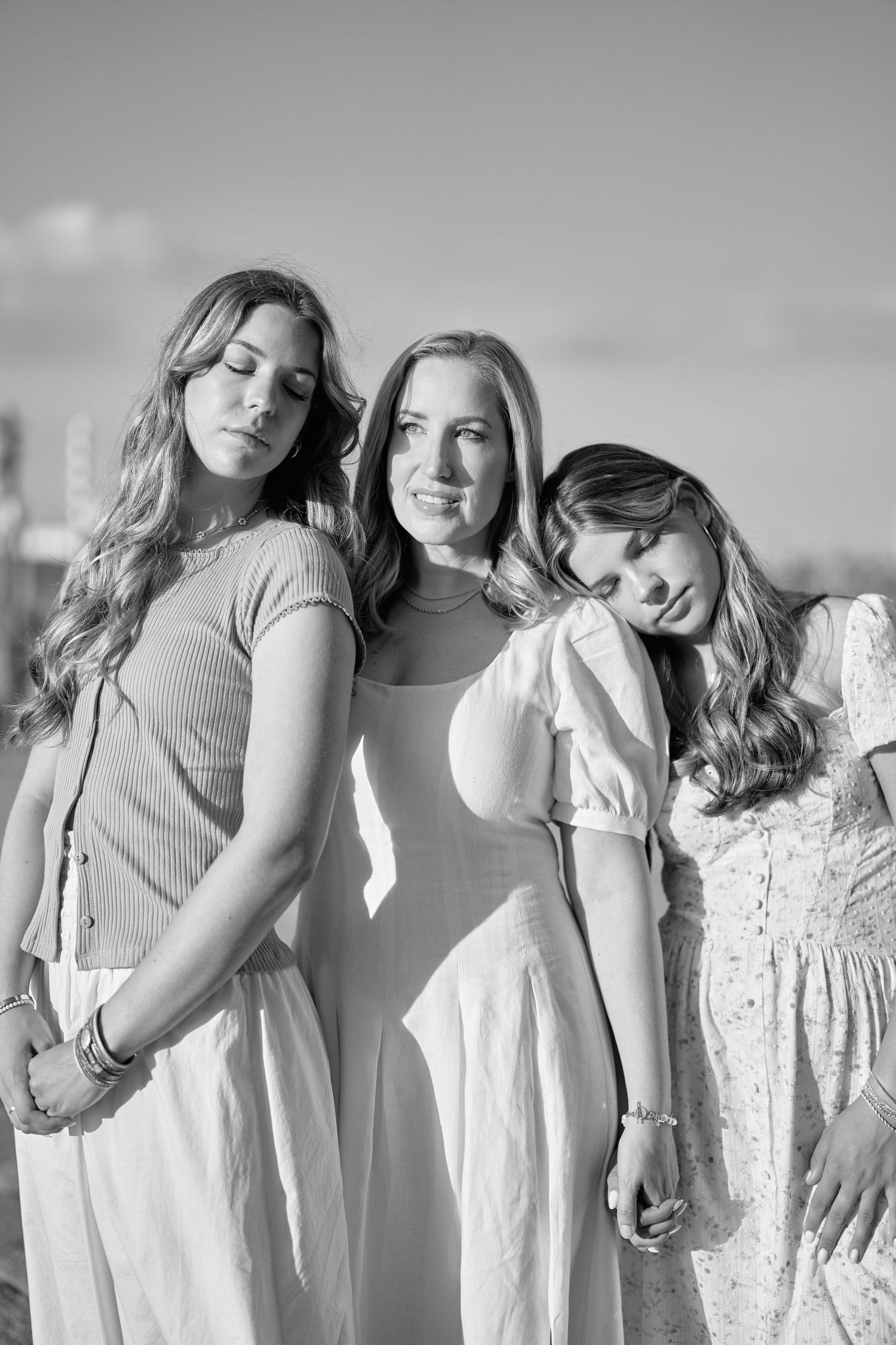 A group of people wearing white dresses stand together in an artistic black and white photograph.