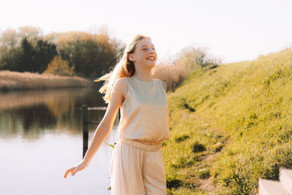 Spontane communiefoto van een lachend meisje aan het water in West-Vlaanderen.