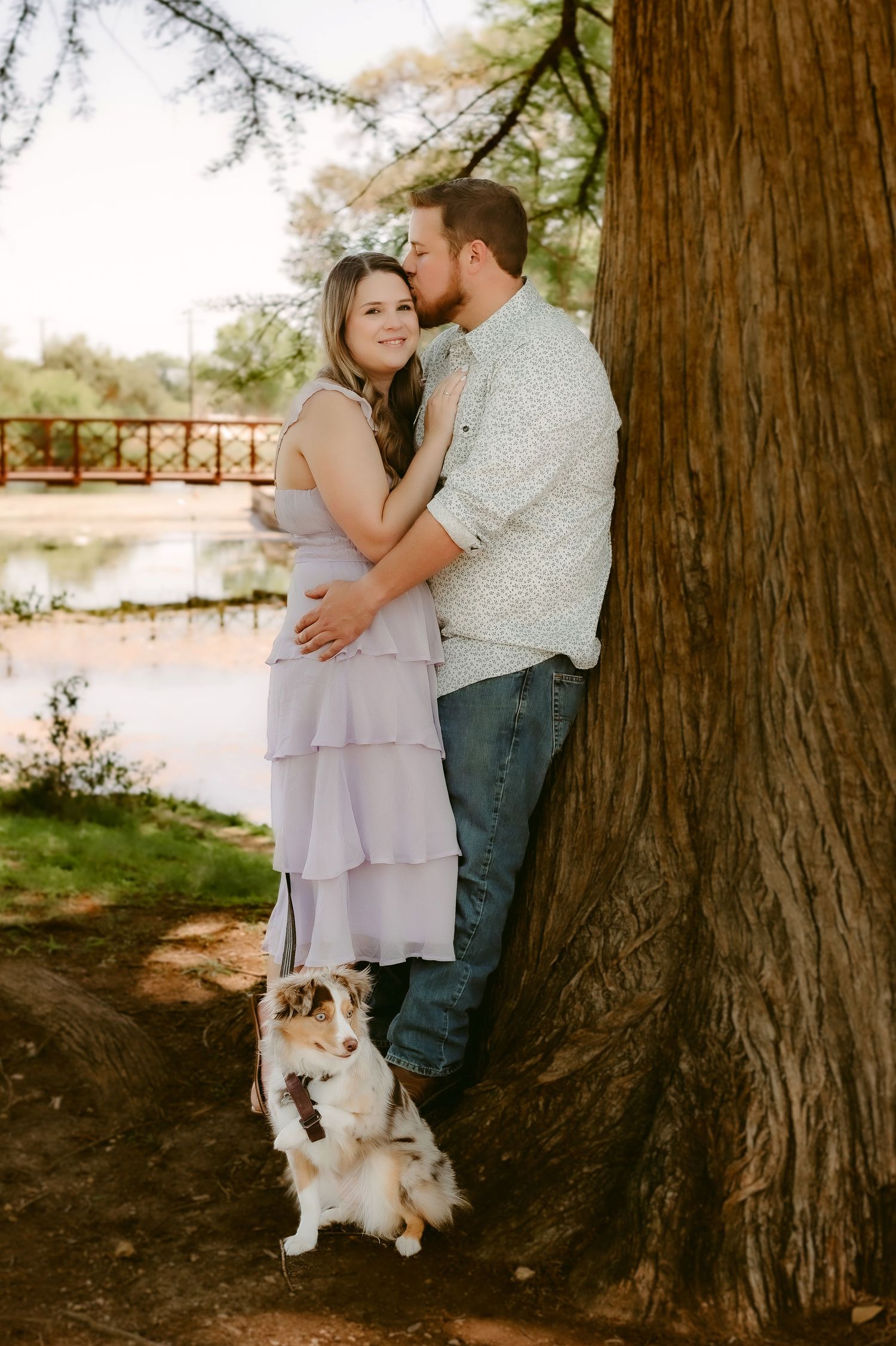 A couple relaxes together on a blanket under dappled sunlight in a peaceful park setting.