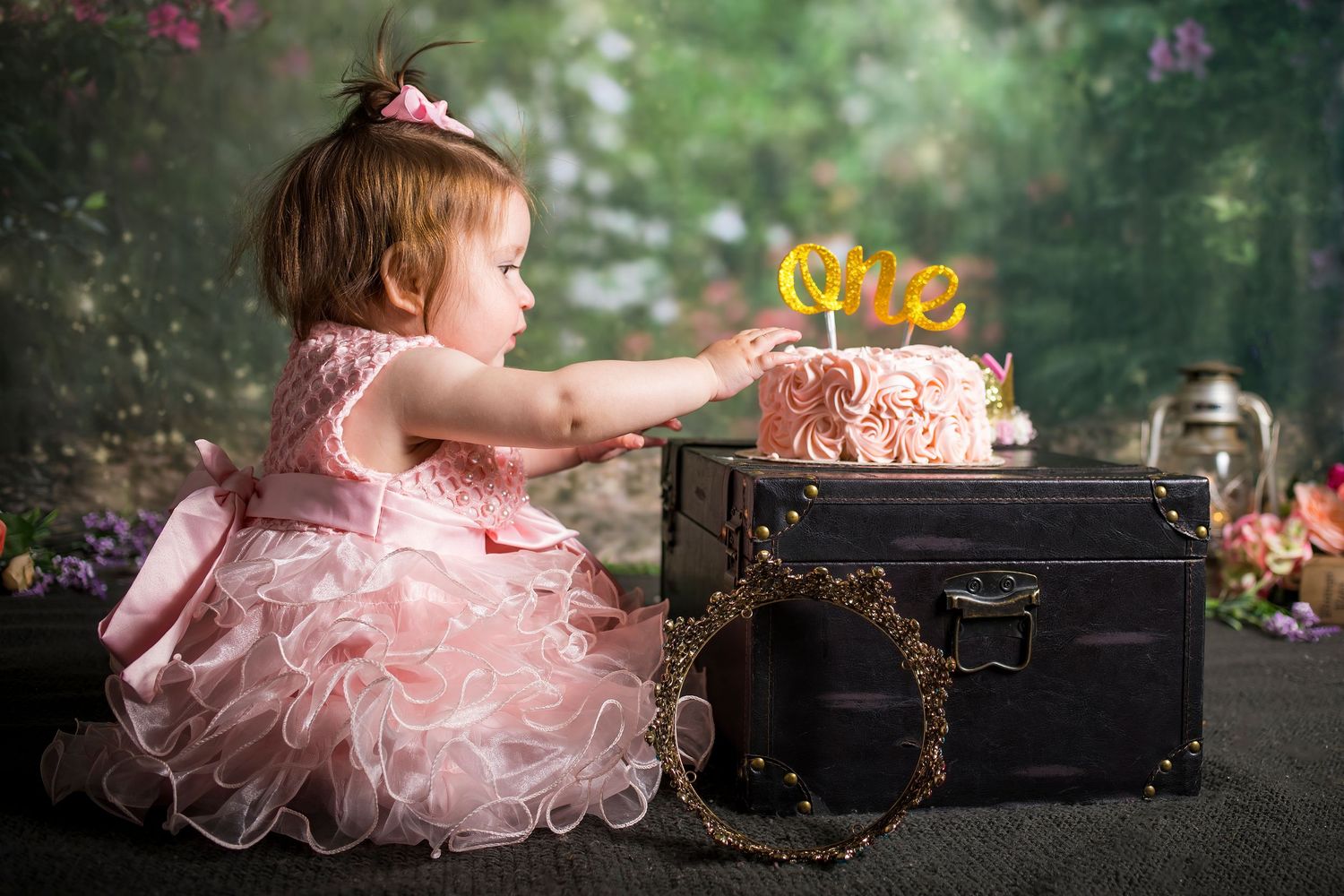 A child in a lace dress sits on a vintage white and red step stool against a dark backdrop.