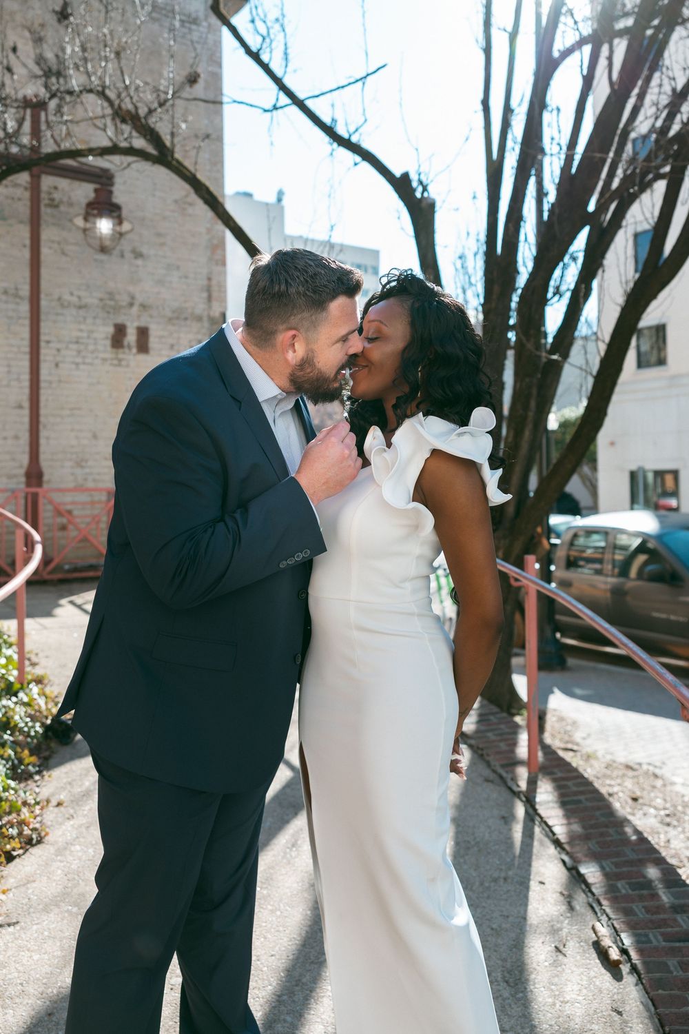 A romantic wedding couple shares intimate kisses in a series of outdoor portraits against a rustic brick wall.