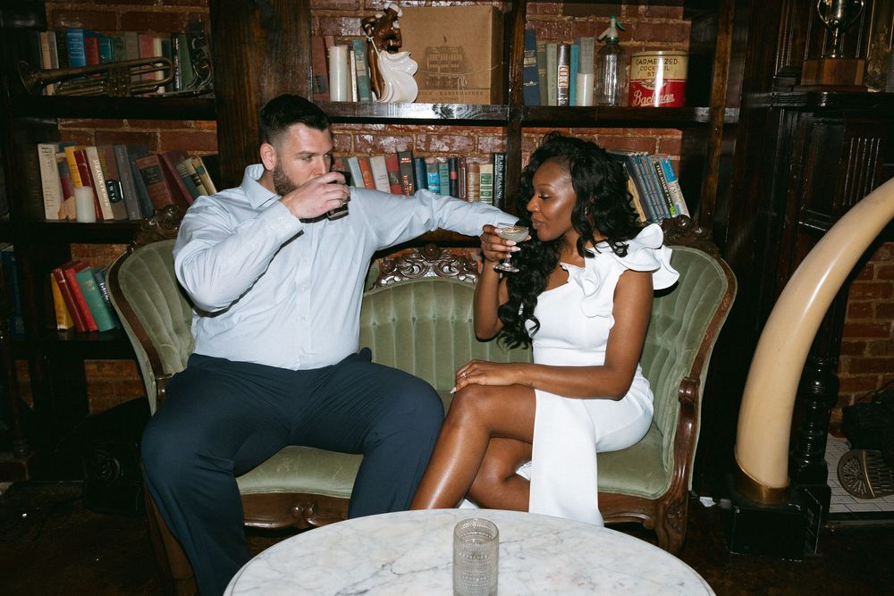 A couple shares a romantic dance together in a dimly lit room with bookshelves in the background.