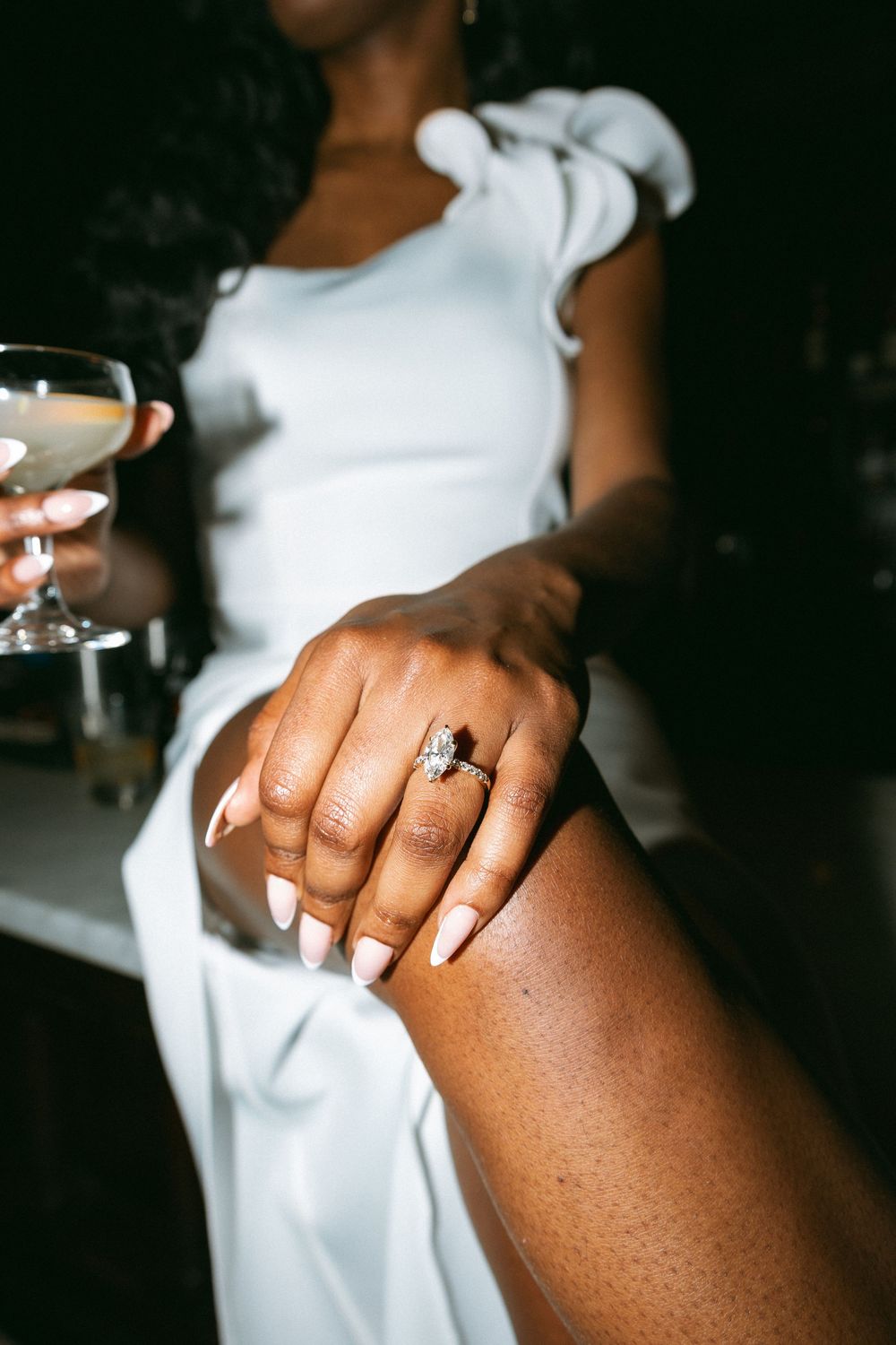 Close-up shots of an engagement ring on a woman's hand wearing a white dress.