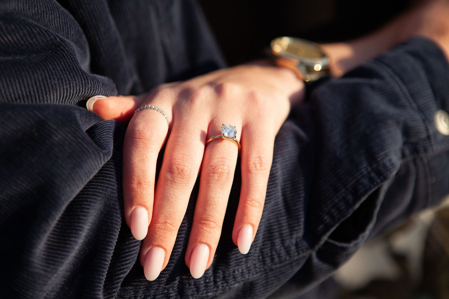 A couple embraces in a romantic outdoor photoshoot with the new engagement ring on her hand