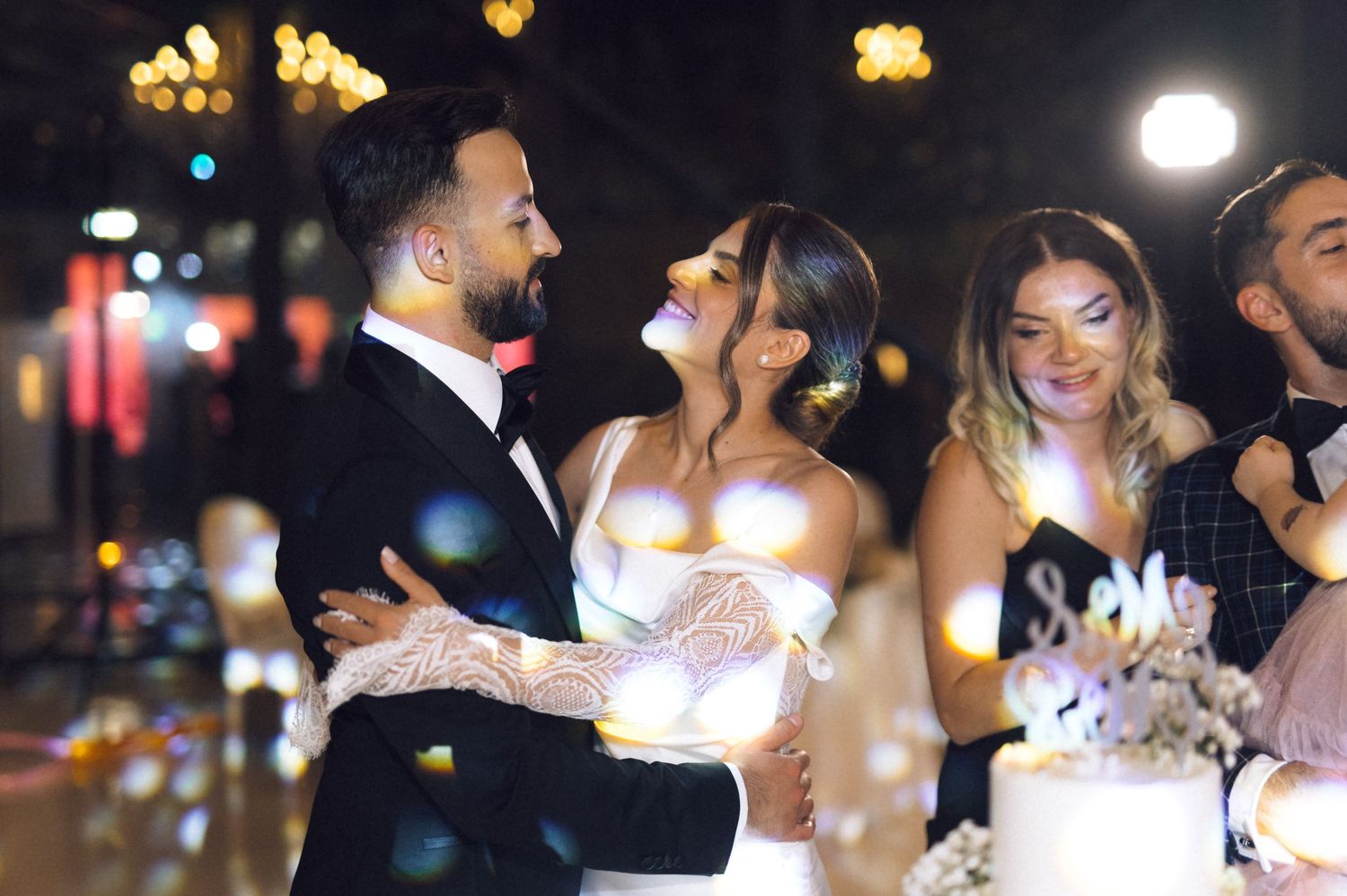 Bride and groom share a joyful moment cutting their wedding cake at an elegant evening reception.