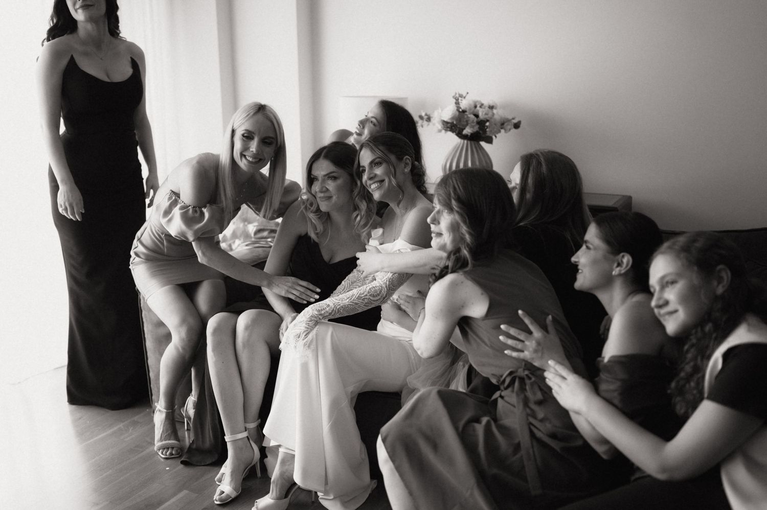 Bride and bridesmaids laughing together taking a selfie in black and white wedding photo.
