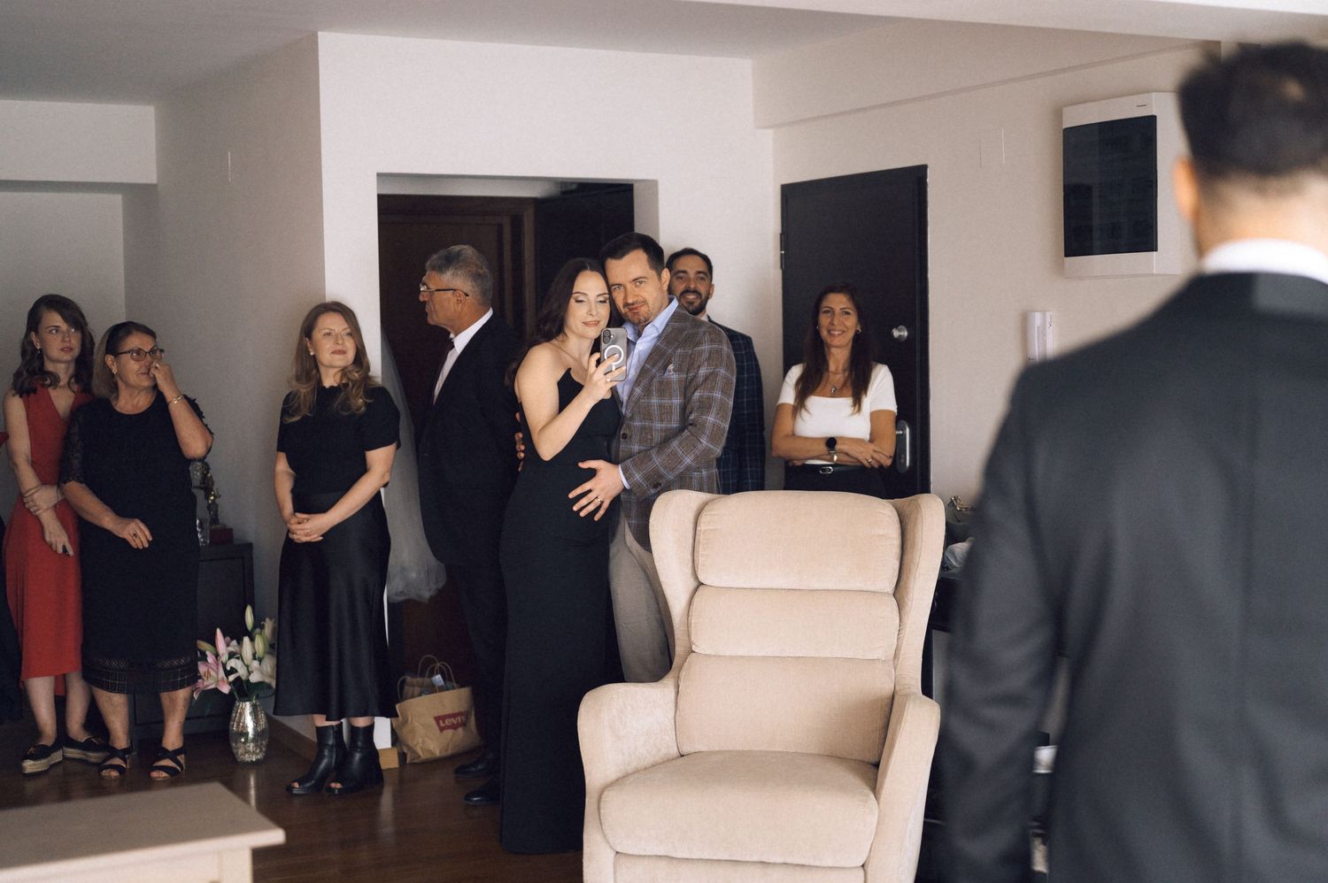 Elegant gathering of guests in formal attire socializing in a modern living room during a special celebration.