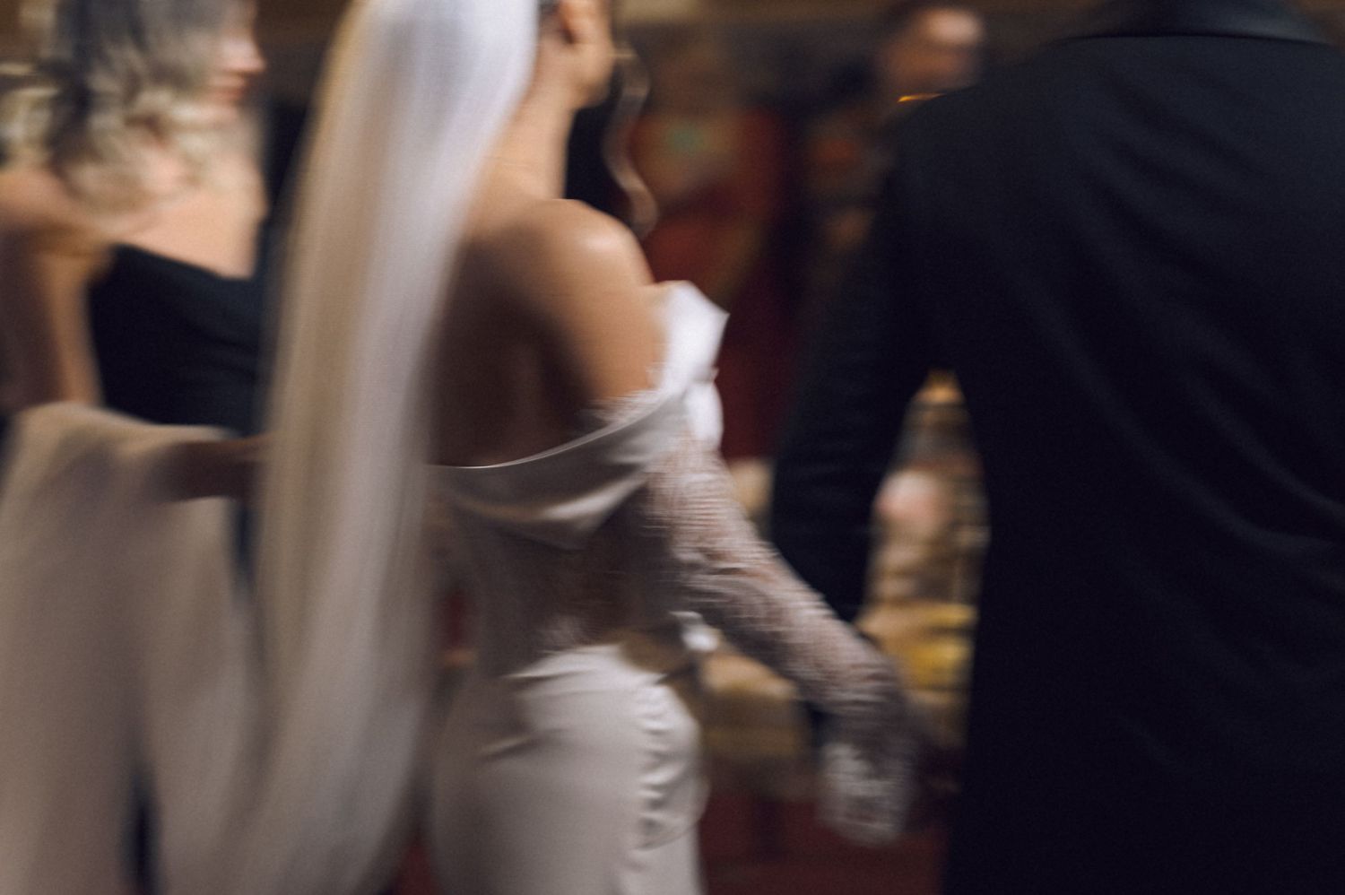 Bride in white off-shoulder gown and veil dancing with groom at elegant wedding reception.