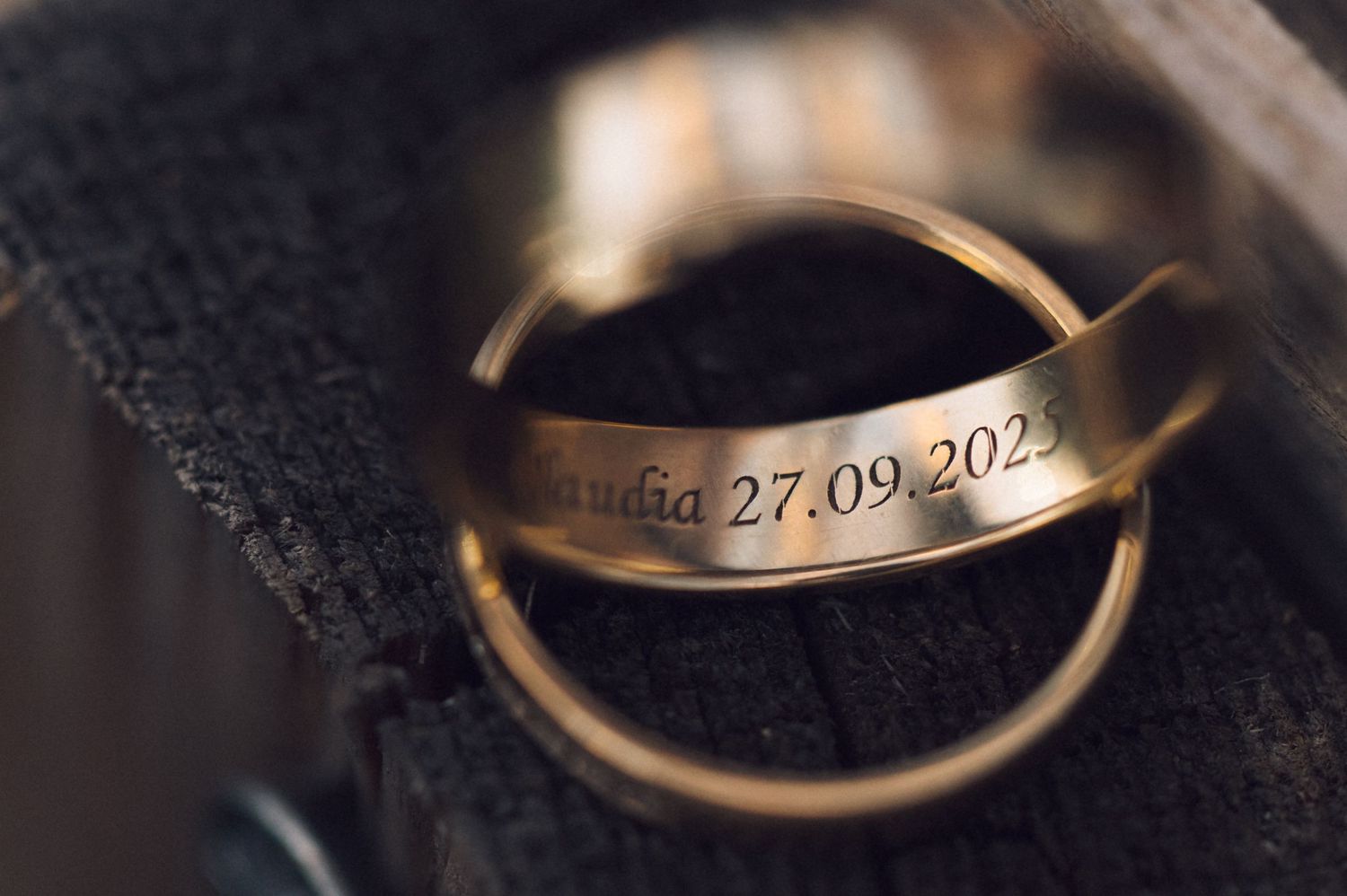 Close-up of gold wedding rings engraved with the name Claudia and date 27.09.2023.